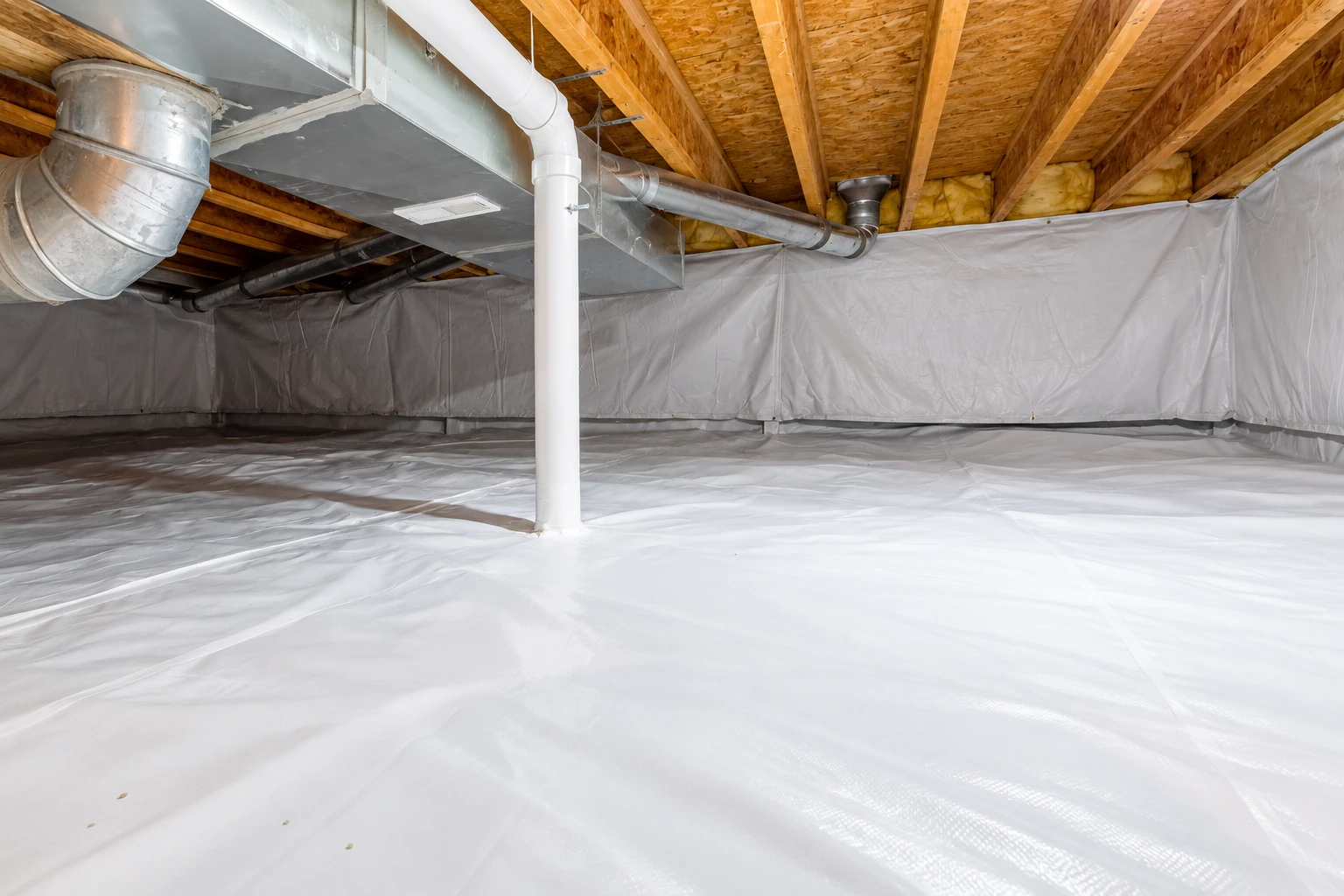 Crawl space with white vapor barrier covering the floor and walls beneath exposed joists and ductwork.